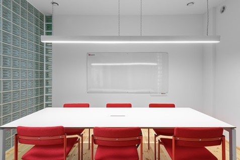 An office with good overhead lighting, red chairs and a table.