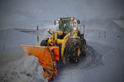 person operating a front loader, pushing the snow away