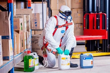 A professinal cleaner in a hazmat suit with his equipment and cleaning products.