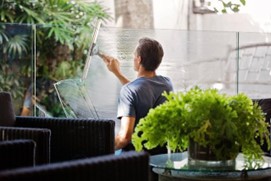 man cleaning a glass surface in a commercial space with a lot of plants